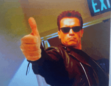 arnold schwarzenegger is giving a thumbs up in front of an exit sign