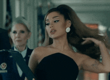 ariana grande in a black strapless dress is holding a clipboard