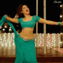 a woman in a blue crop top and a blue skirt is dancing