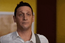 a man in a white shirt and suspenders is making a face