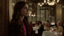 a woman in a red coat stands in front of a netflix ad