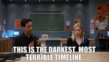 a man and a woman are sitting at a table in front of a blackboard .