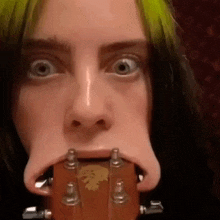 a close up of a woman holding a guitar in her mouth .