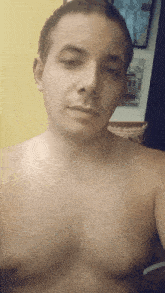 a shirtless man is taking a selfie in front of a yellow curtain