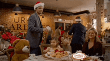 a man in a santa hat is pouring tea into a cup while a little girl looks on