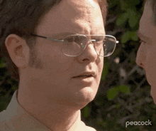 a close up of a man wearing glasses looking at another man 's face .