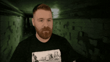 a man with a beard is wearing a black shirt with a picture of a cartoon on it