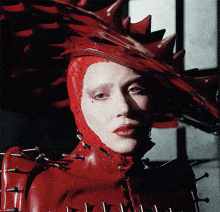 a woman in a red costume with spikes on her arms
