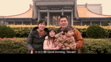 a family posing for a picture in front of a building with the words good morning taiwan on the bottom