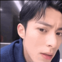 a close up of a man 's face with a blue sweater on